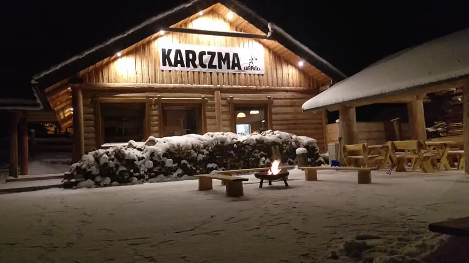 Karczma Karpatka wieczorem, z ogniskiem i miejscami siedzącymi na stoku